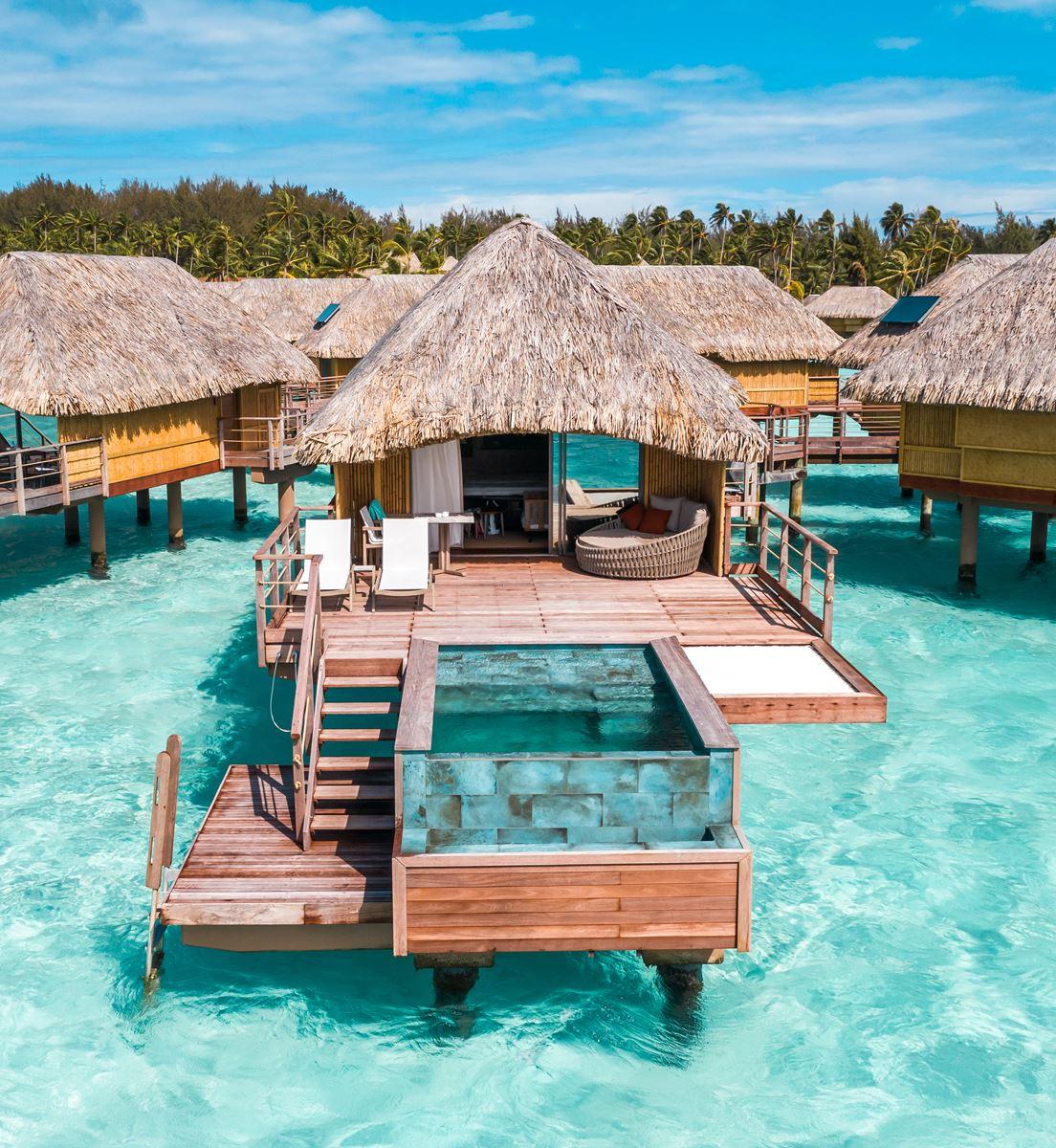 Overwater bungalows extending into crystal turquoise waters with Mount Otemanu views