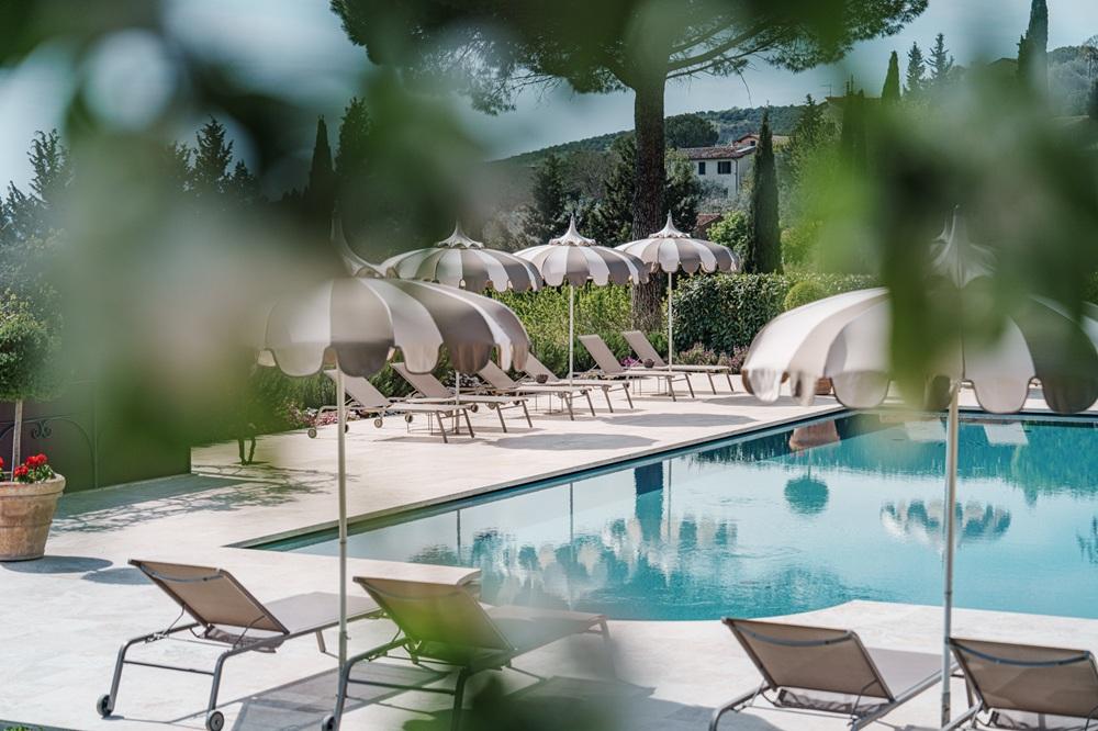 Panoramic outdoor swimming pool framed by local marble and Tuscan countryside views
