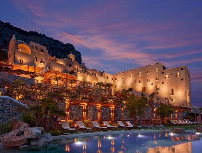 Illuminated Monastero Santa Rosa glowing atop cliffs at night
