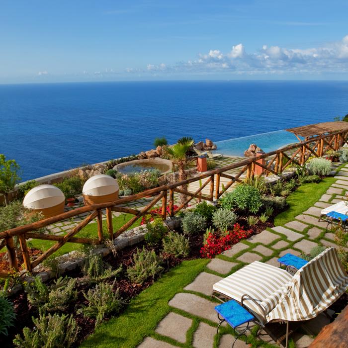 Heated infinity pool carved directly into rock face over the Mediterranean Sea