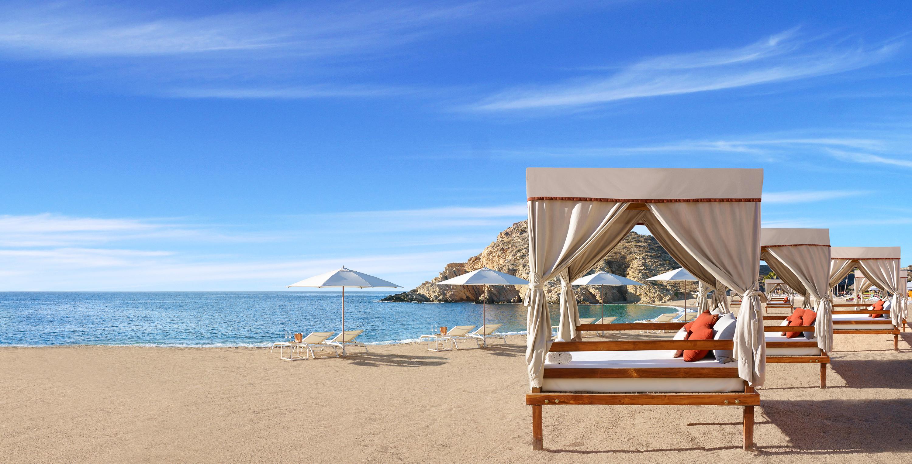 Plush beach daybeds on the golden sands of swimmable Santa Maria Bay