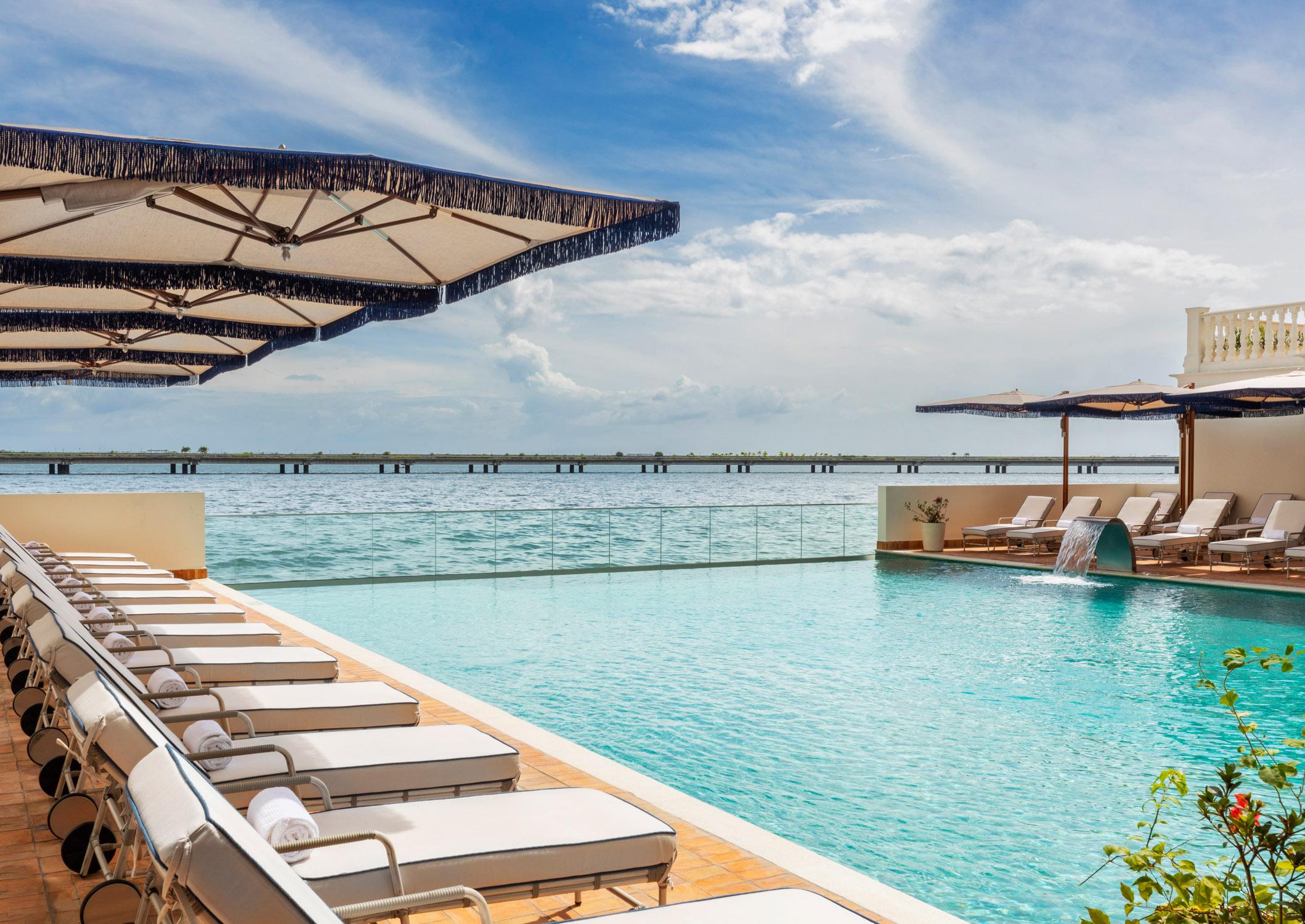 Waterfront infinity swimming pool with comfortable sun loungers directly overlooking the Pacific