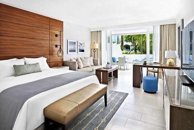 Poolside Villa king bedroom with floor-to-ceiling glass doors leading out to tropical garden sun decks