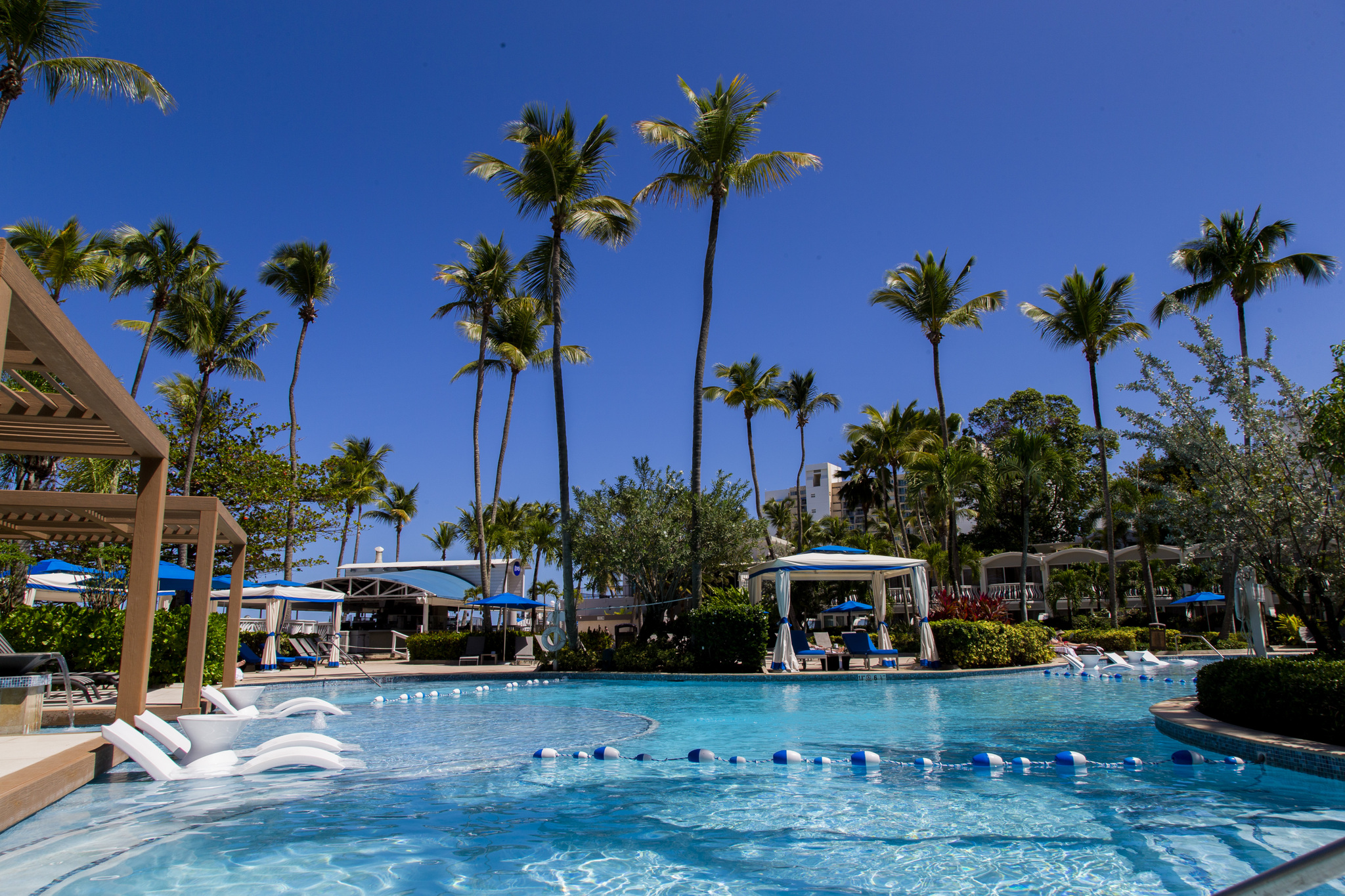 Sprawling freeform outdoor lagoon swimming pool with swim-up bar and sunny terrace daybeds