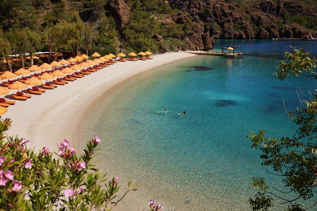 Pristine private white sand at Maris Beach with sun loungers and crystal-clear waters