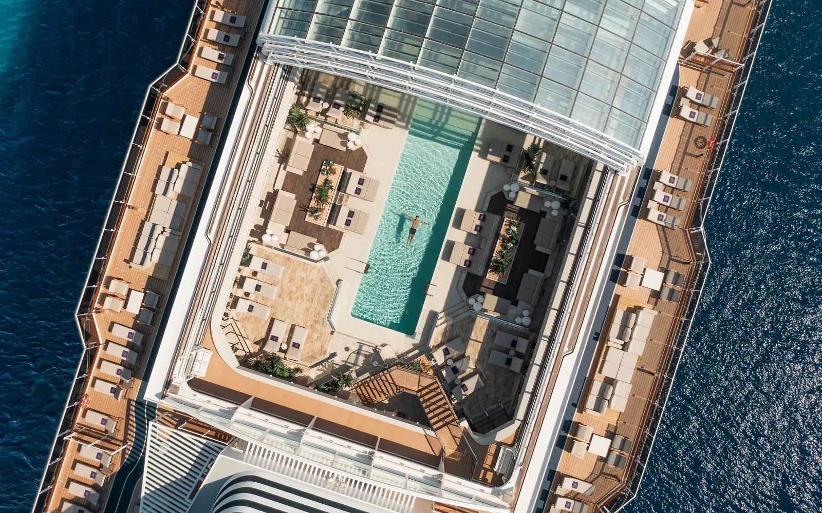 Explora Journeys Conservatory Pool under a retractable glass roof with poolside cabanas