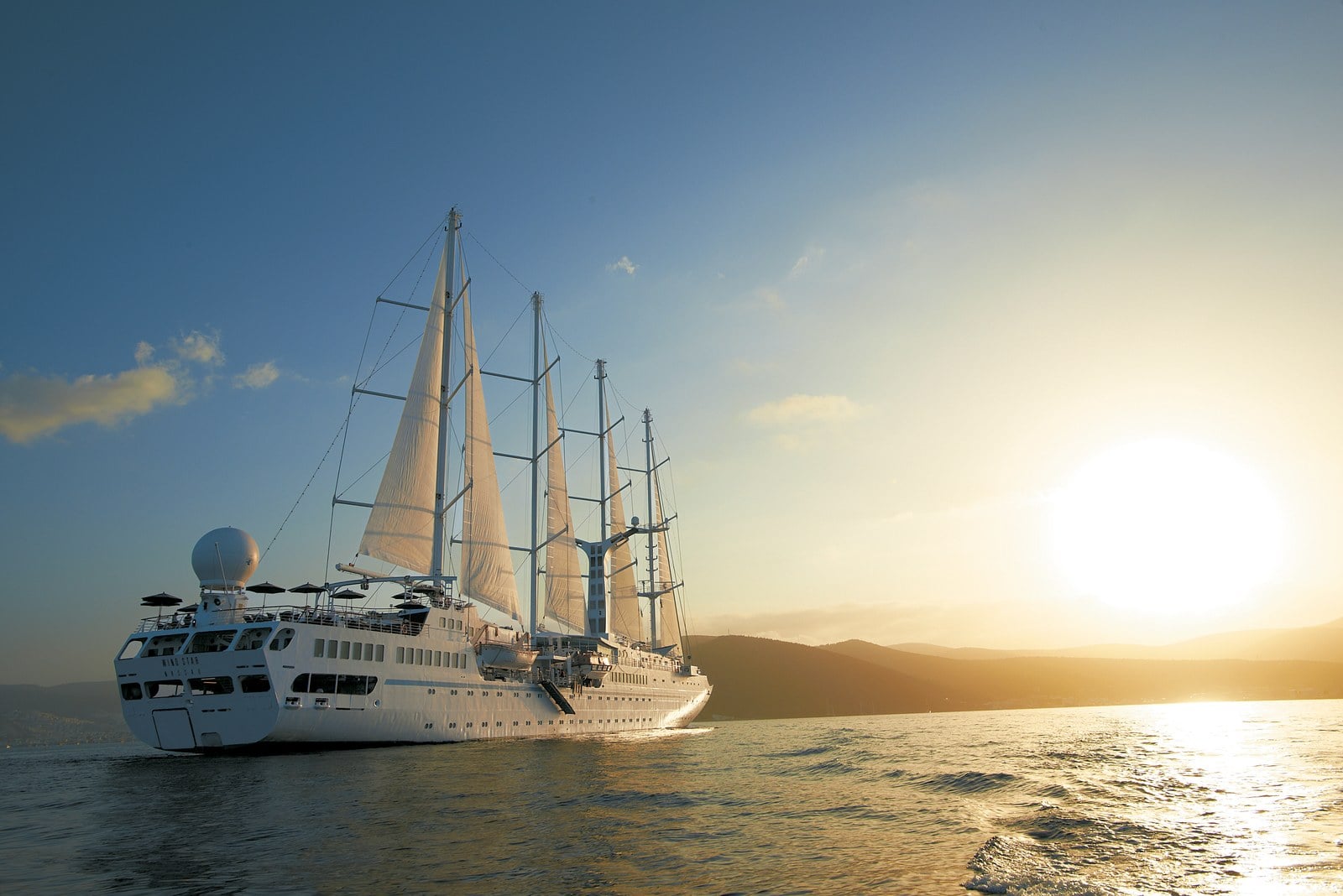 Windstar Cruises Wind Surf five-masted flagship sailing under billowing white sails