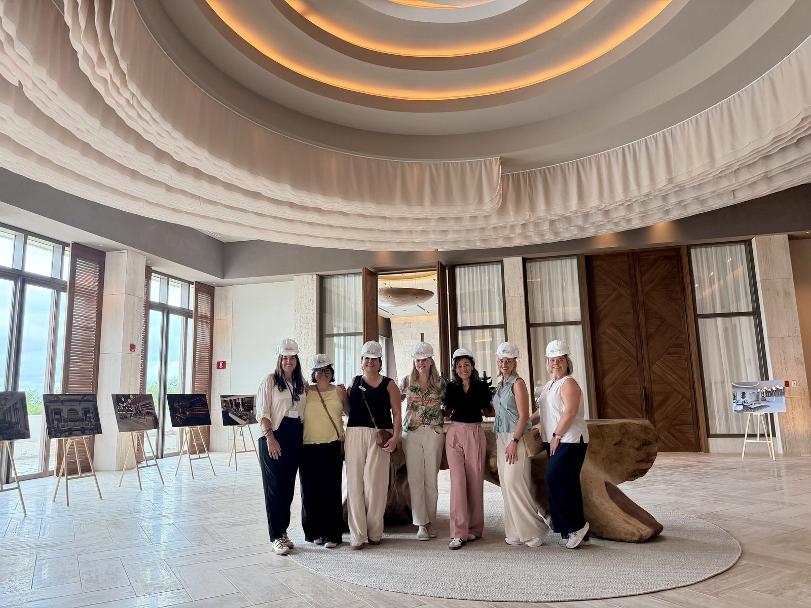 Vincent Vacations team in the rotunda preview lounge with architectural renderings and monumental timber table