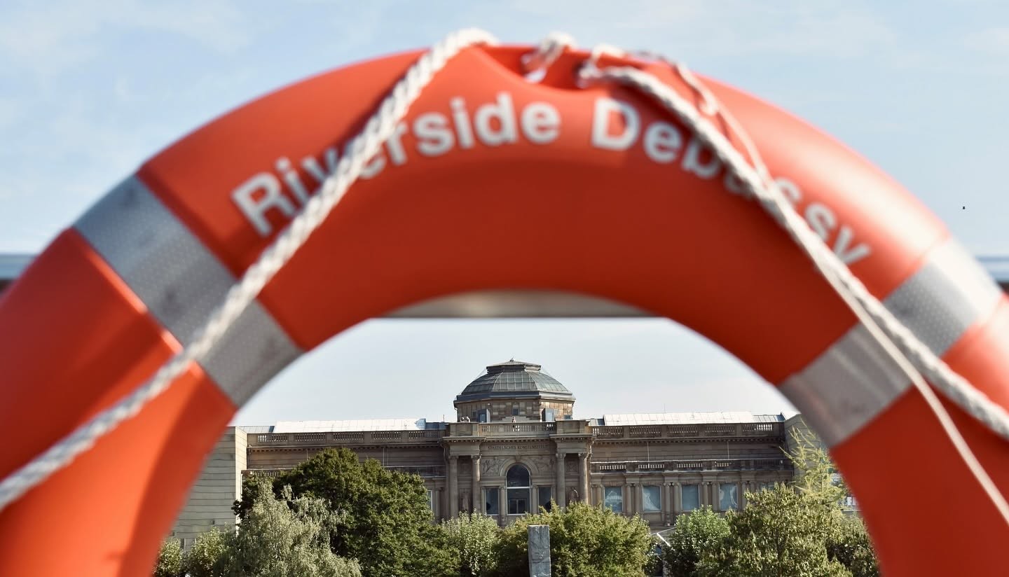 Riverside Debussy life ring on ship railing overlooking historic European riverfront