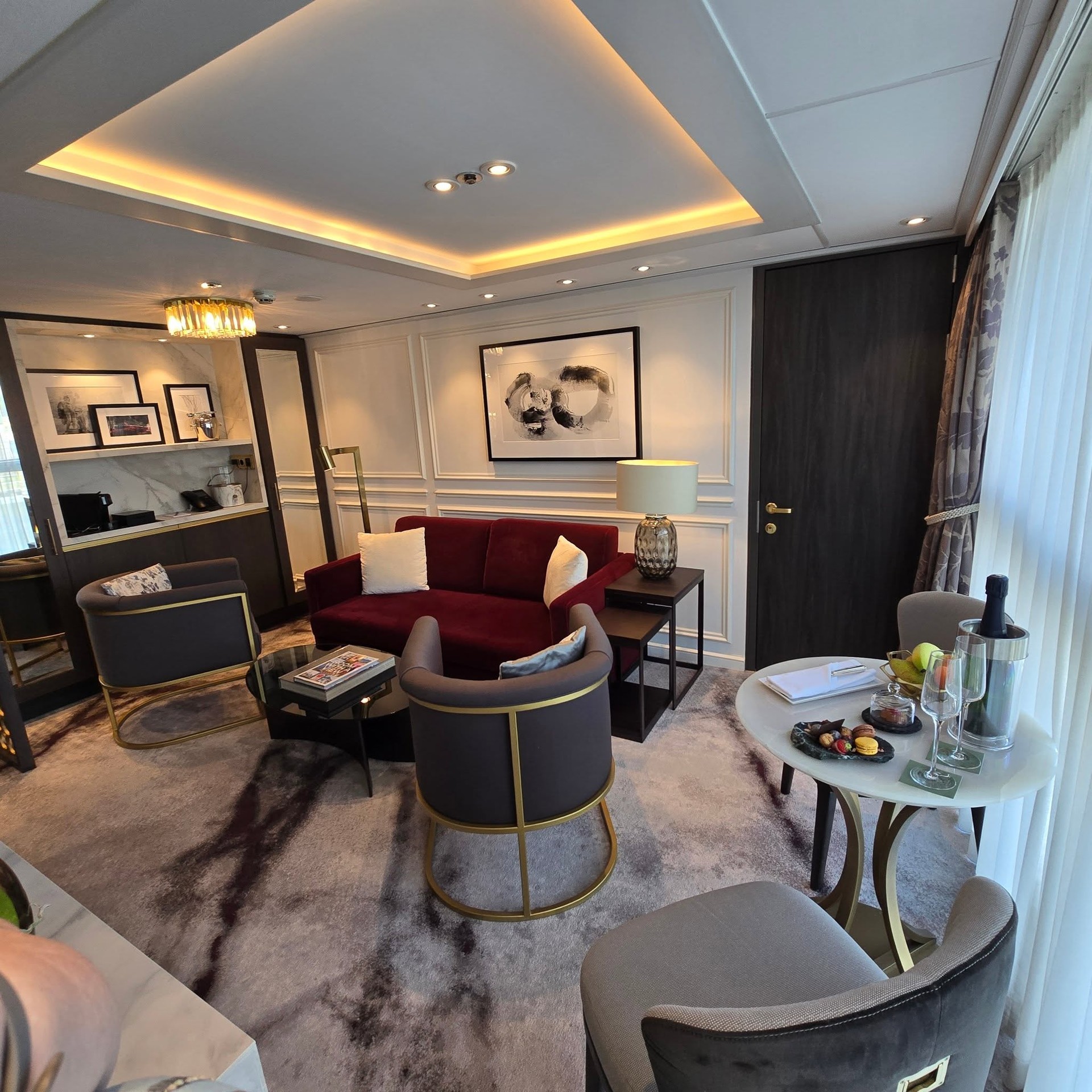 Riverside Debussy Suite grand living room with velvet armchair, circular table, and chandelier
