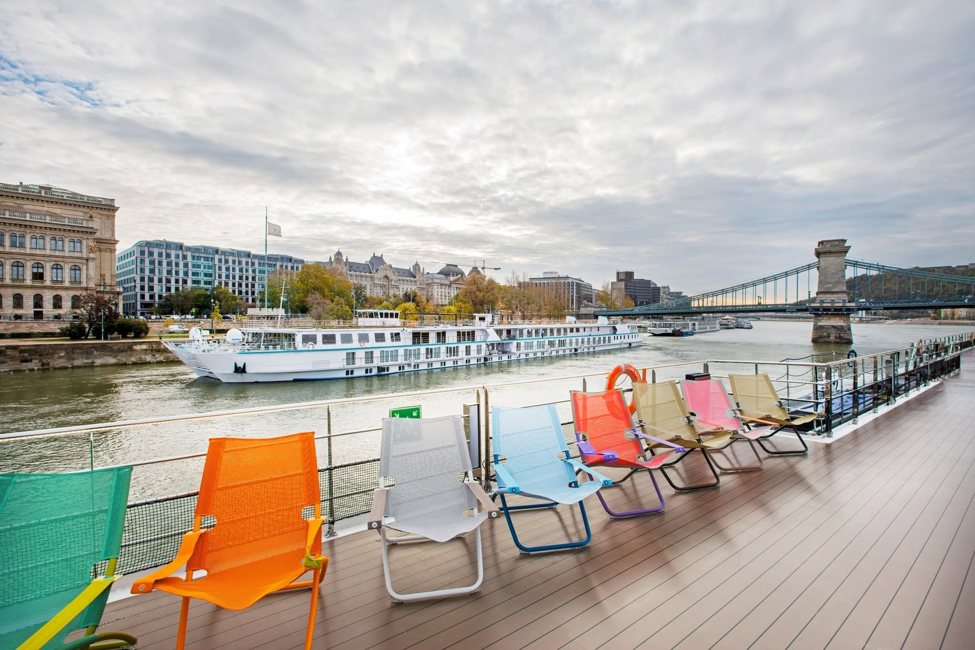 Colorful sun deck loungers overlooking the Danube in Budapest with Chain Bridge on Riverside Debussy