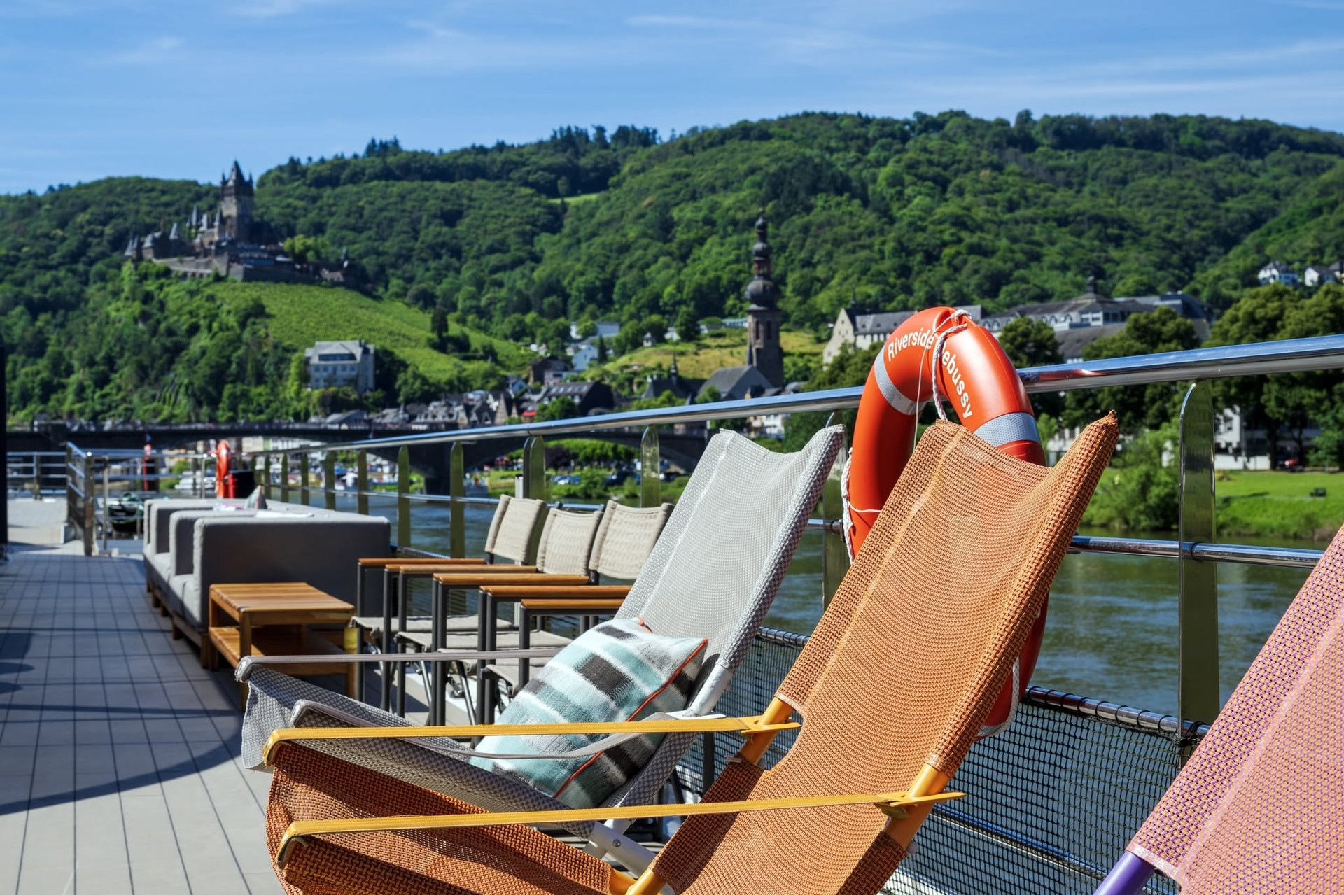 Wooden sun loungers facing hillside castles and vineyards in Rhine Gorge on Riverside Debussy