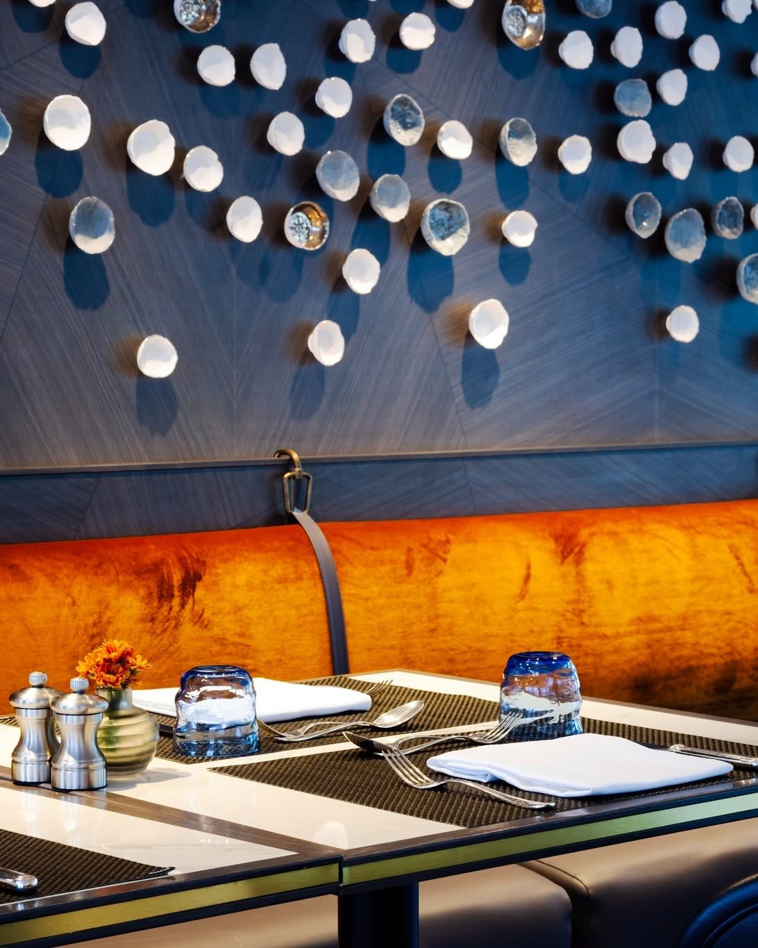 Intimate dining table with bespoke porcelain wall installation aboard Riverside Luxury Cruises