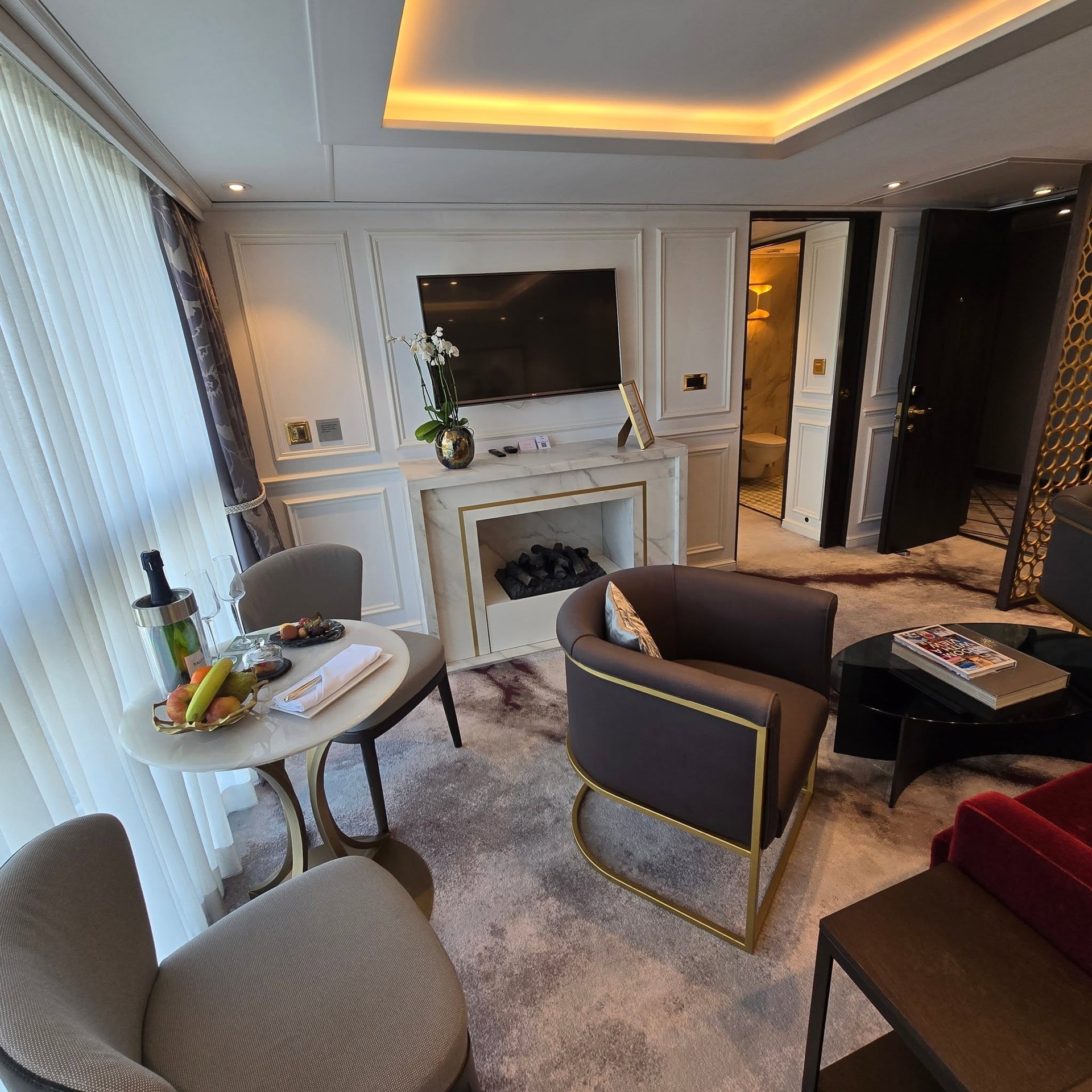 Suite living room with ambient fireplace, armchairs, and welcome champagne on Riverside Debussy