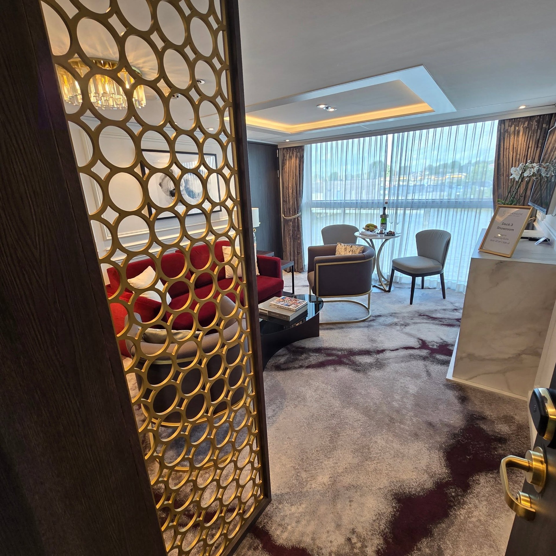 View through decorative gold lattice partition into suite seating salon on Riverside Debussy
