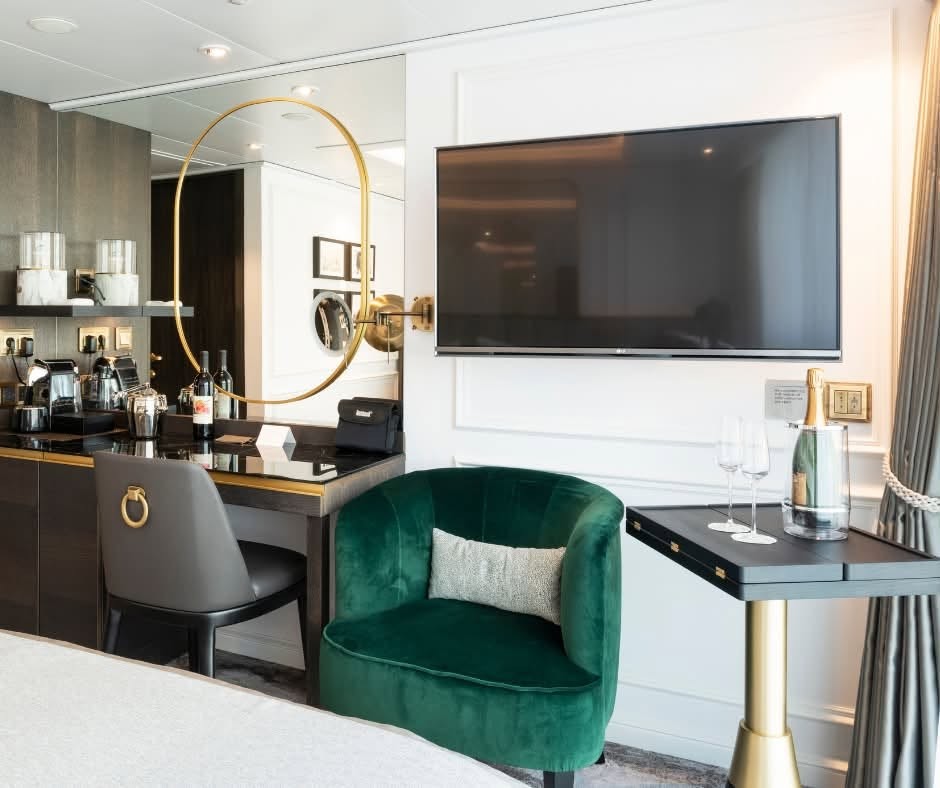Suite bar setup with Nespresso machine, green velvet armchair, and flat-screen TV on Riverside Debussy