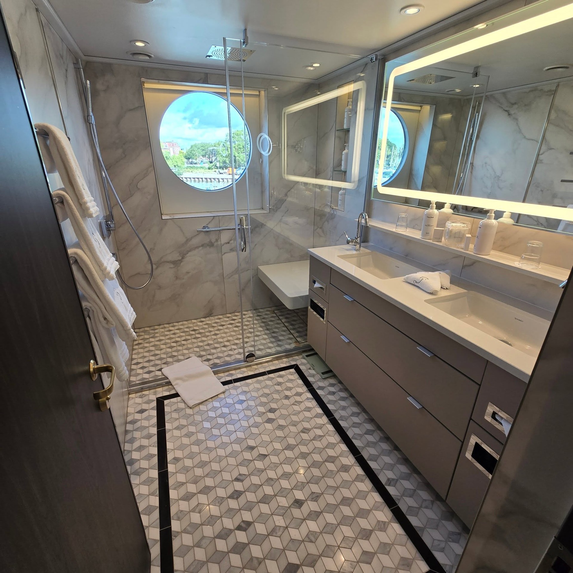 Palatial master bathroom with nautical porthole window and double vanity on Riverside Debussy