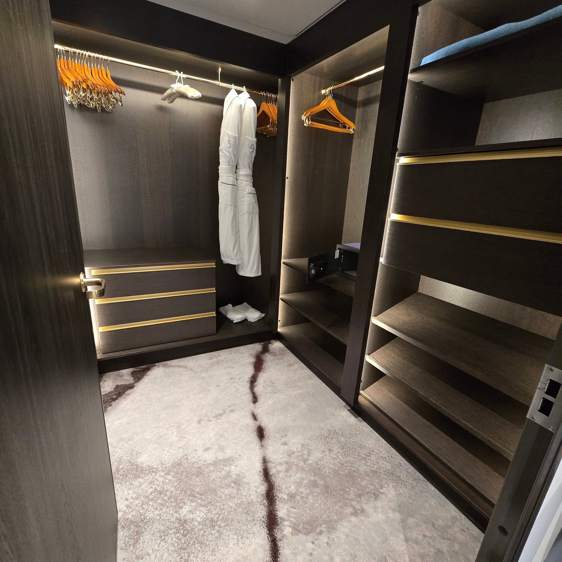 Spacious walk-in wardrobe with plush bathrobes and custom shelving on Riverside Debussy