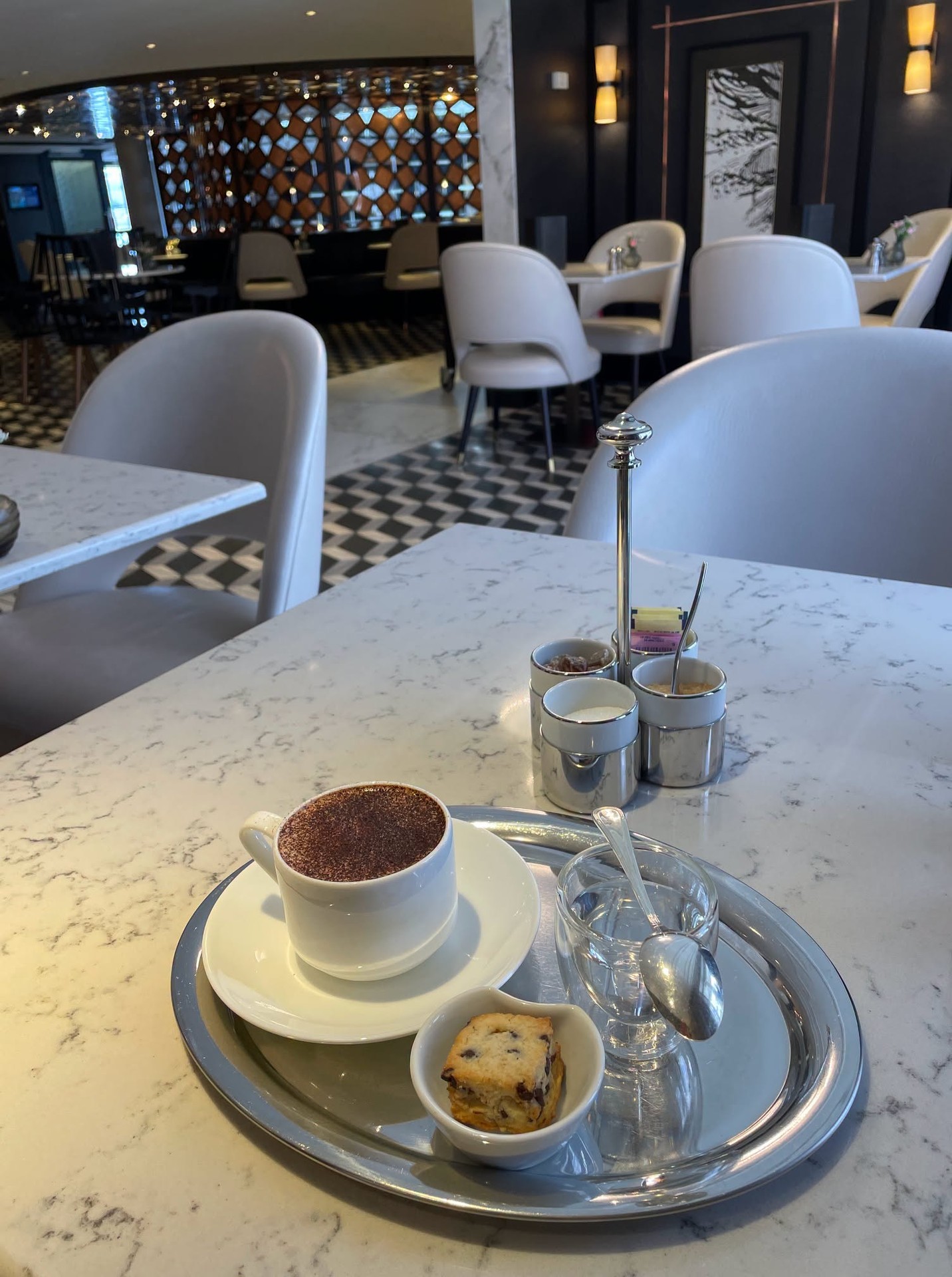 Traditional European coffee service with silver tray and chocolate on marble cafe table