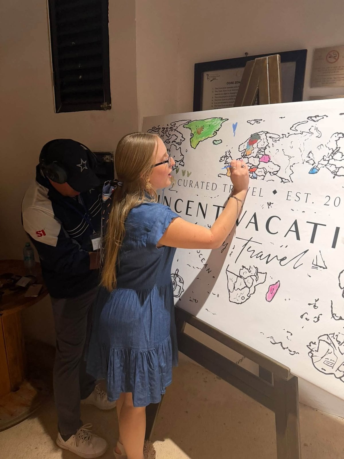Collaborative art: advisor hand-coloring the custom Vincent Vacations Curated Travel world mural