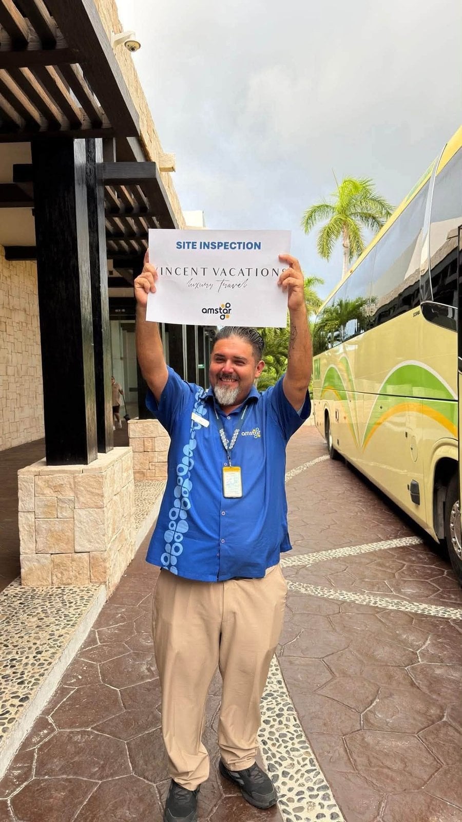 Amstar tour guide holding Vincent Vacations site inspection sign next to luxury coach bus