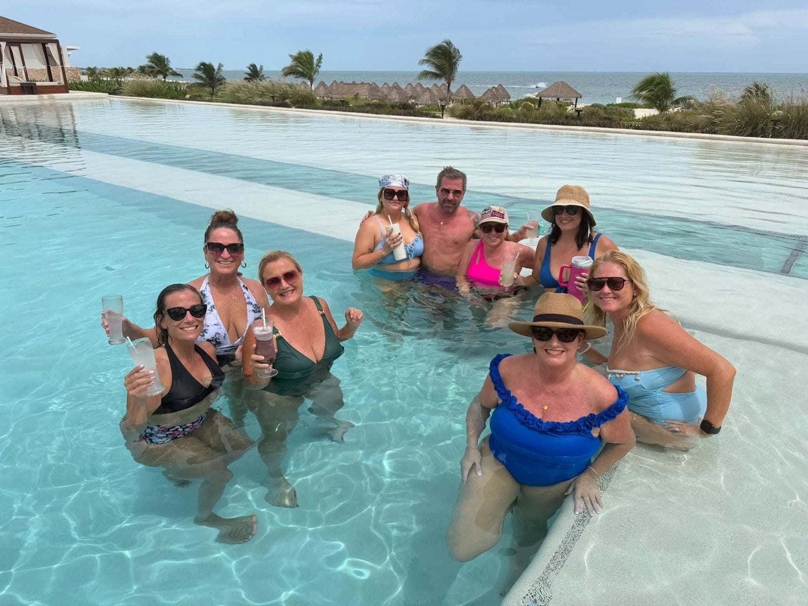 Vincent Vacations travel advisors toasting in the oceanfront infinity pool at Dreams Playa Mujeres