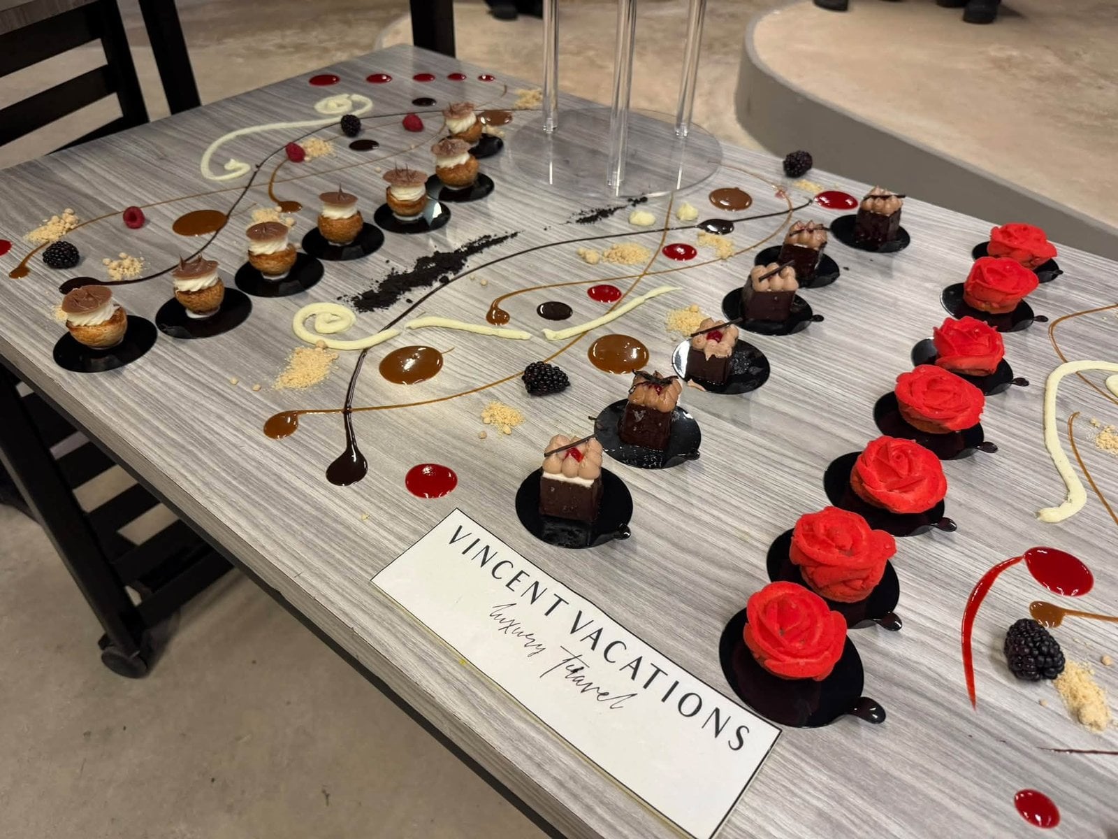 Gourmet welcome dessert table with chocolate roses and Vincent Vacations Inspiring Travel logo
