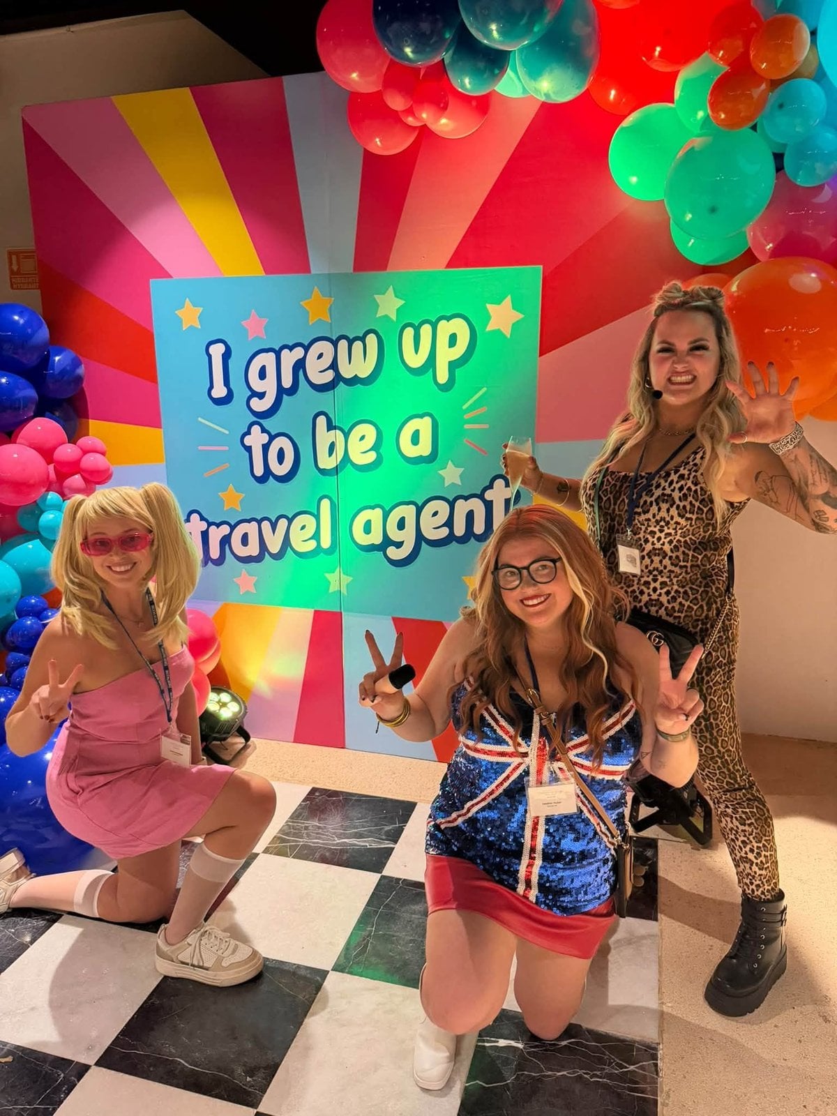 Travel advisors dressed in childhood dream costumes under the When I Grow Up To Be A Travel Agent arch