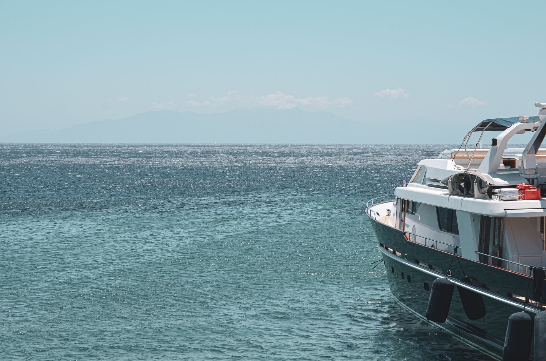 Sleek Luxury White Superyacht Anchored in Turquoise Bay of Greek Islands