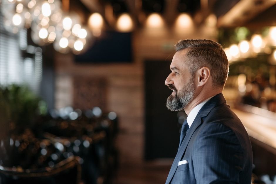 Top producing luxury travel advisor smiling in modern executive travel agency workspace