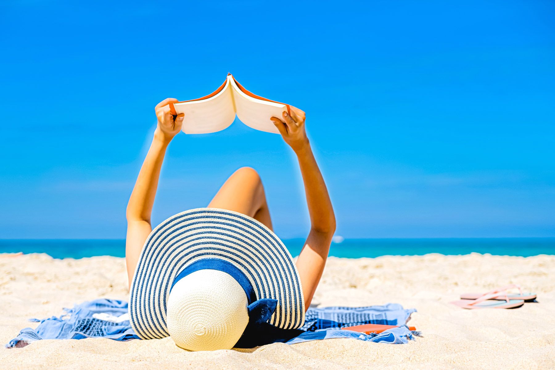 woman reading book beach