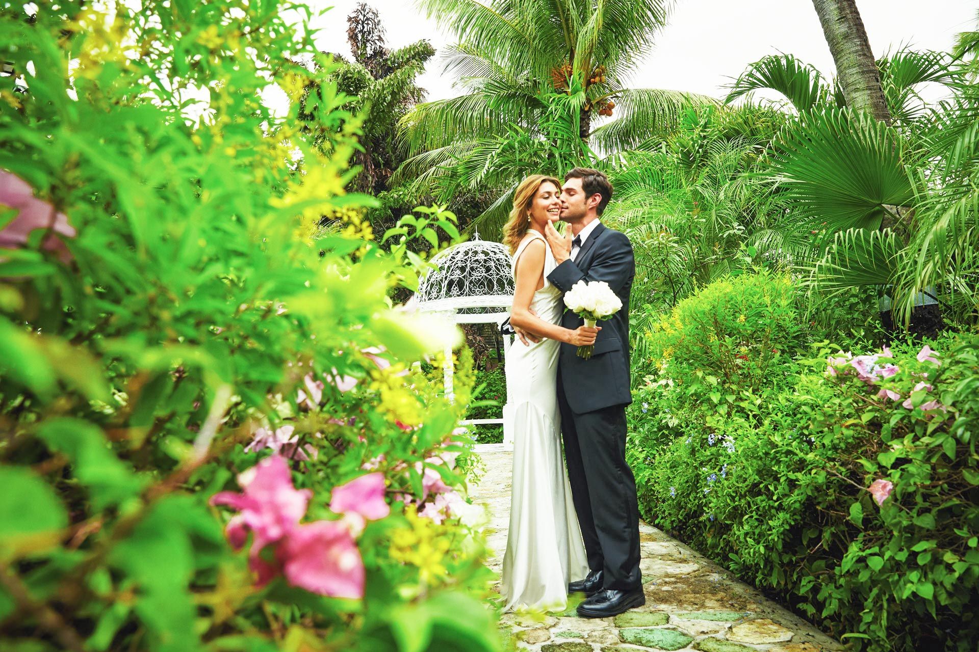 Wedding couple in gardens kissing