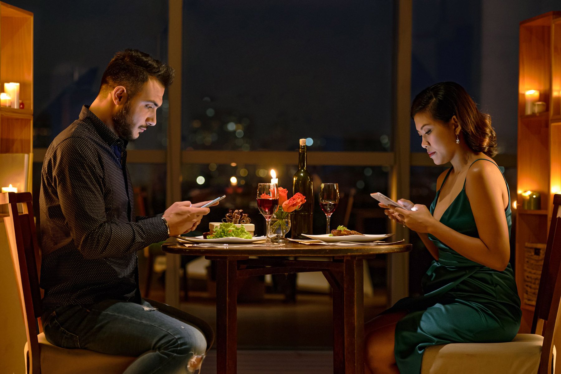 young couple using phones during date