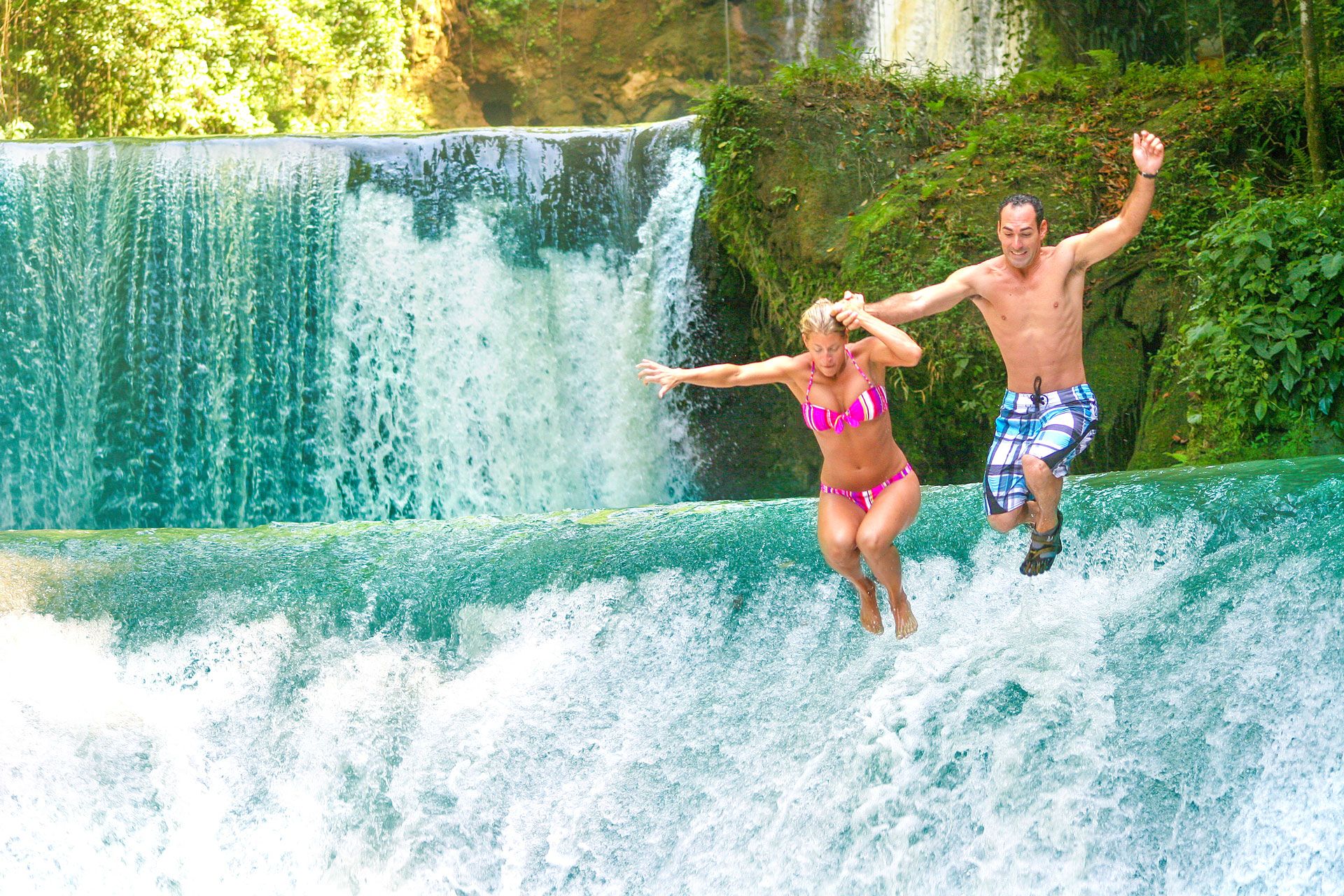 couple jumping from waterfall jamaica