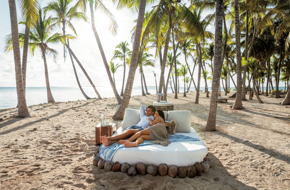couple on a beach day bed at sandals royal bahamian