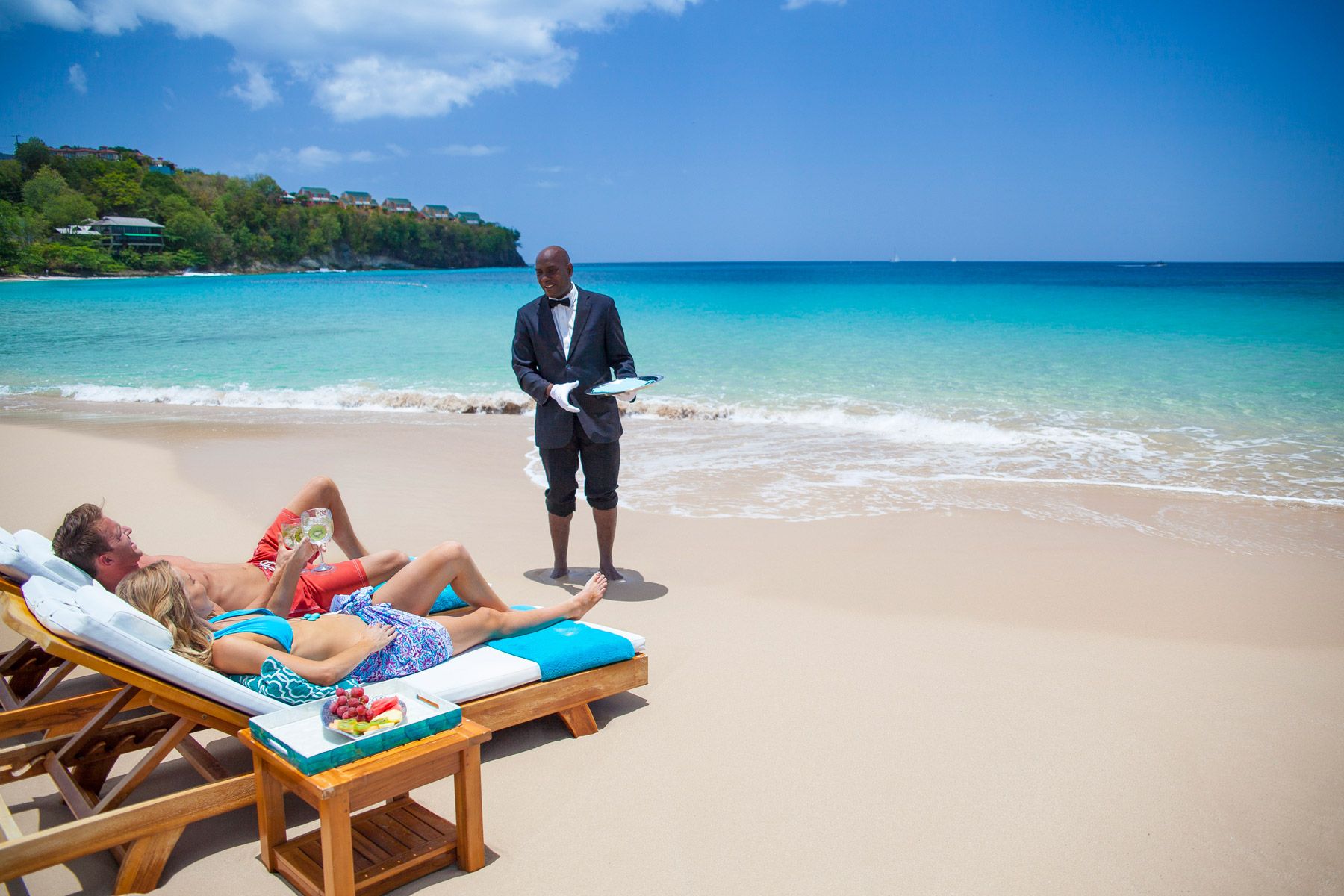 couple enjoying butler service at beach in sandals regency la toc