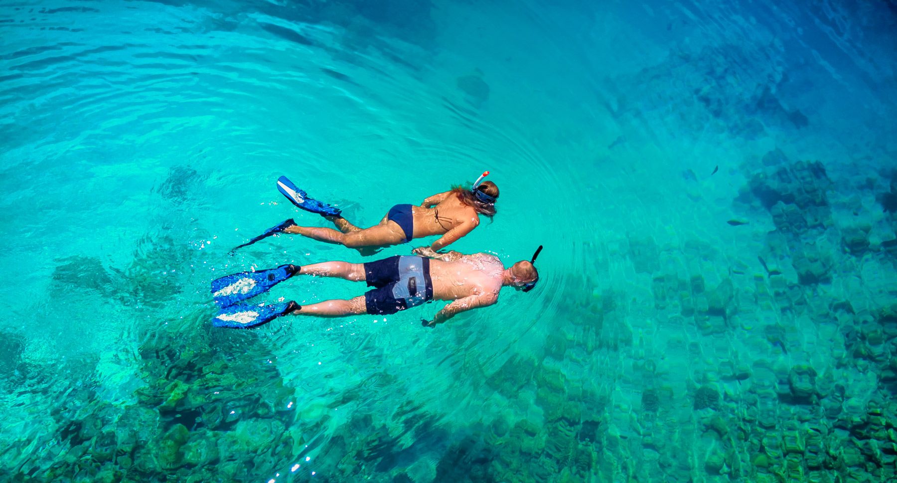 top view of couple snorkeling in clear tropical waters